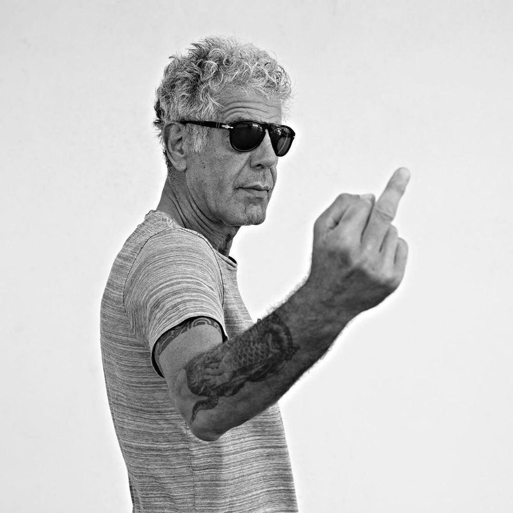 Anthony Bourdain casually, without spite, middle finger raised.