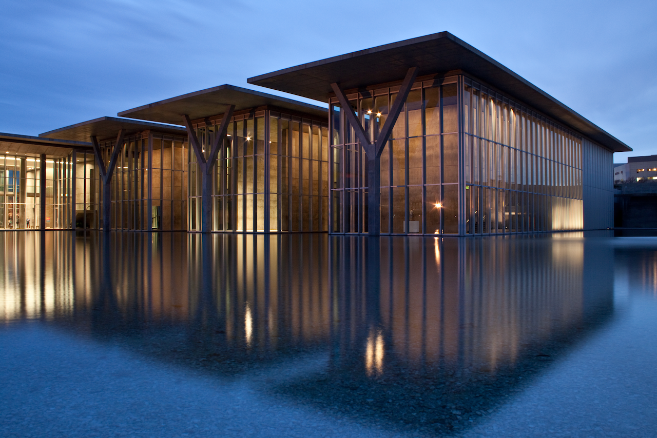 Modern building with glass facade reflecting water at night. Modern Art Museum of Fort Worth.
